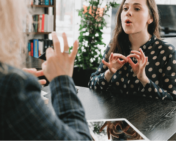 Deux femmes, face à face, sont en train de discuter en langue des signes