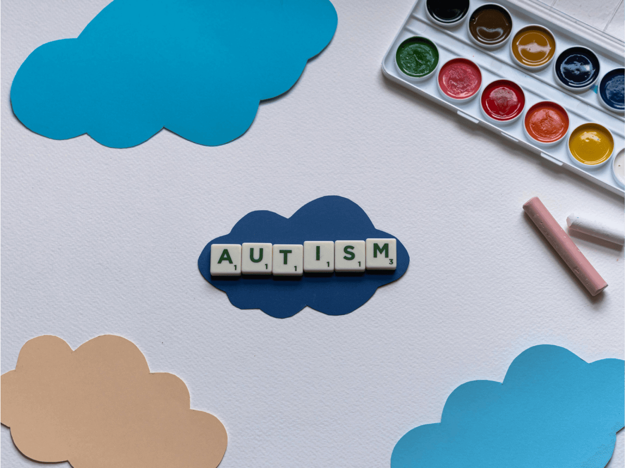 Des nuages. Des lettres de scrabble, posées sur le nuage central, forment le mot «autisme» 